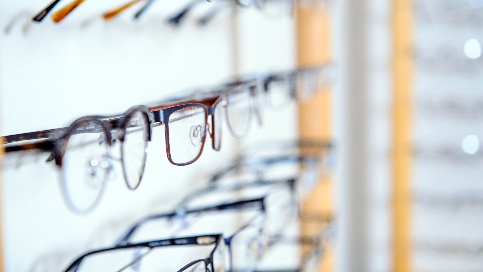 In einem Optikergeschäft – verschiedene Brillen, die in einem Wandregal zum Verkauf angeboten werden